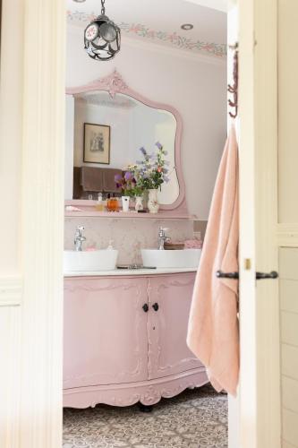 a pink bathroom with a sink and a mirror at Petit Château luxe vakantiehuis, prive hottub en zwembad in Heythuysen