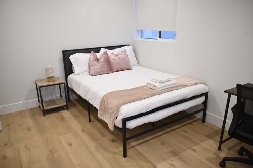a bedroom with a bed with pink pillows on it at Luxe Ensuite in Shared Home-Minutes to USC in Los Angeles