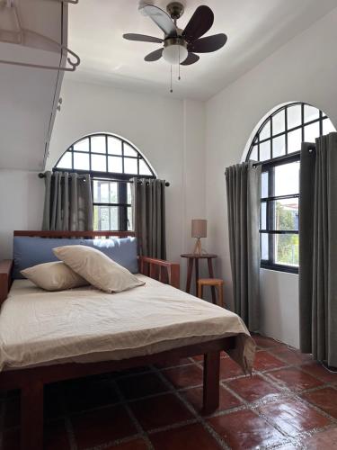a bedroom with a bed with two windows and a ceiling fan at Serenita Tagaytay in Kibagan