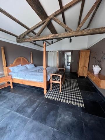 a bedroom with a wooden bed and a chair at La Ferme Suntala Bari in Panaoti