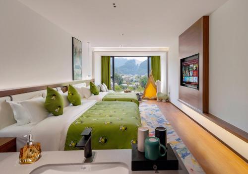 a bedroom with a large bed with a green blanket at Zhangjiajie National Park East Gate Happy Hotel-River View&City Center&Book Tickets&English Speaking&Free Laundry in Hanqiyu