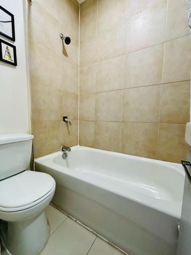 a bathroom with a toilet and a white bath tub at The Skyline Luxury Unit in Bélanger