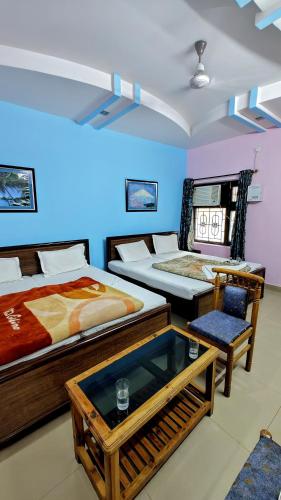 a room with three beds and a table and chairs at Hotel Aryaman in Haridwār