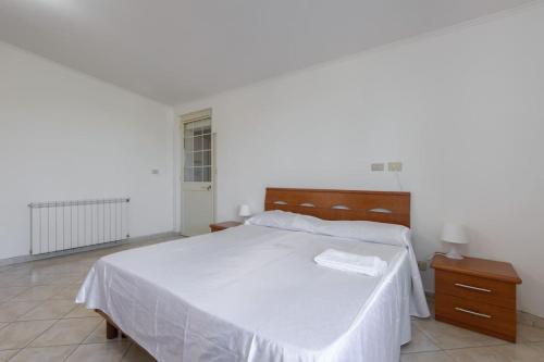 la casa di Anna... في Olgiata: غرفة نوم مع سرير أبيض كبير و كومودينو