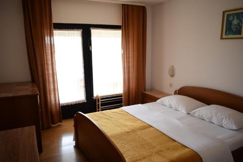 a bedroom with a large bed and two windows at Rooms Vila Mautner in Vodice