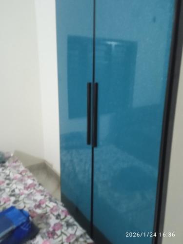 a blue glass cabinet sitting next to a bed at Haven roots in Trivandrum