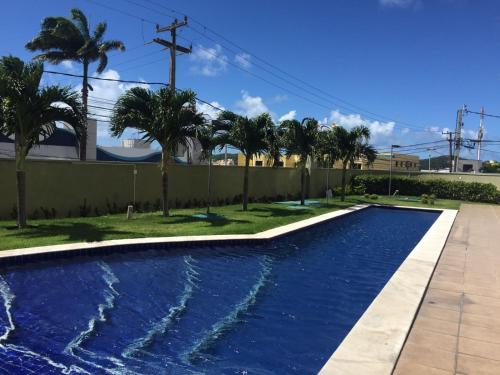 a swimming pool with palm trees and a fence at Incrível Vista VIP de Ponta Negra - Morro do Careca do 32º andar in Natal