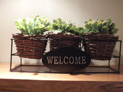 two baskets of flowers on a stand with a welcome sign at Relais Cà Nova Guest House in Bogogno