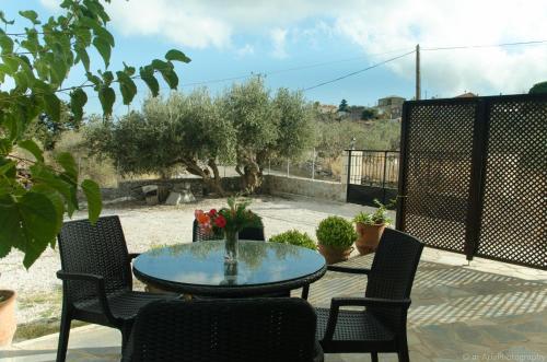 a patio with a table and chairs and some plants at Villa Sunrise in Epáno Kefalás