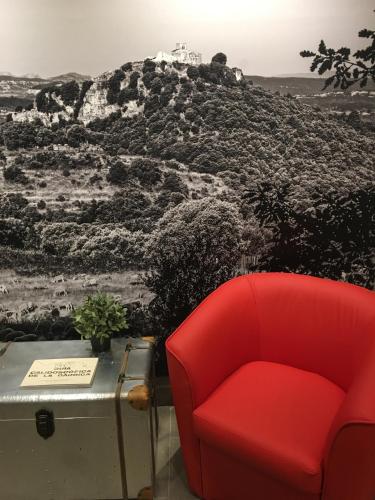 a red chair sitting next to a table with a wall at Hotel Calabria in La Garriga