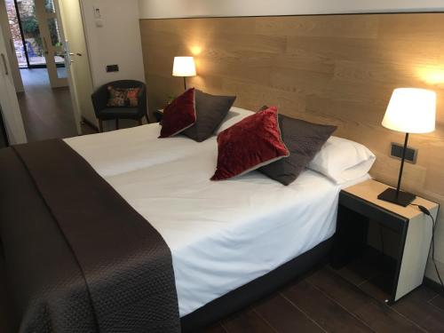 a bedroom with a large white bed with red pillows at Hotel Calabria in La Garriga