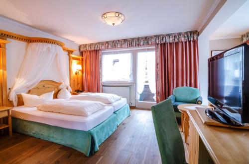 a bedroom with a bed and a flat screen tv at Hotel CENTRAL Bar & Restaurant in Gerlos