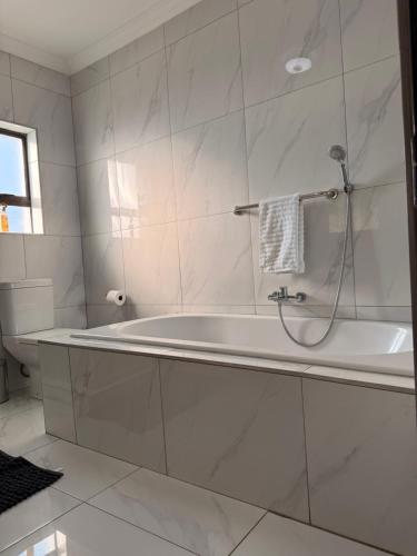 a white bathroom with a tub and a toilet at Dunamis Lodge in Giyani