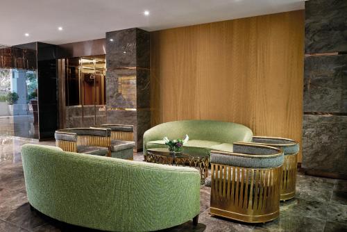 a lobby with green chairs and a table and stools at Dorsett Putrajaya in Putrajaya