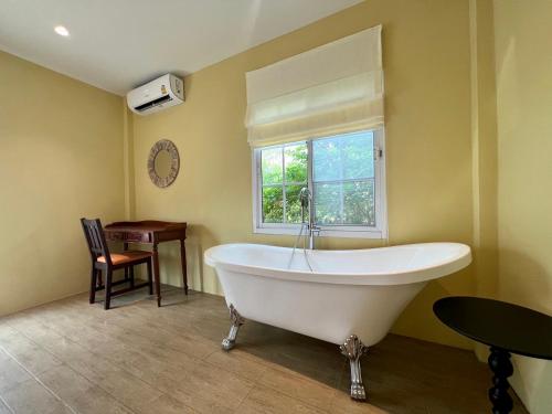 a large white bath tub in a room with a window at Sunset House Khao Yai in Pak Chong