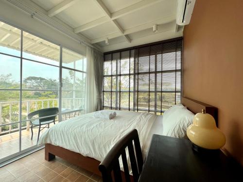 a bedroom with a bed and a table and a window at Sunset House Khao Yai in Pak Chong