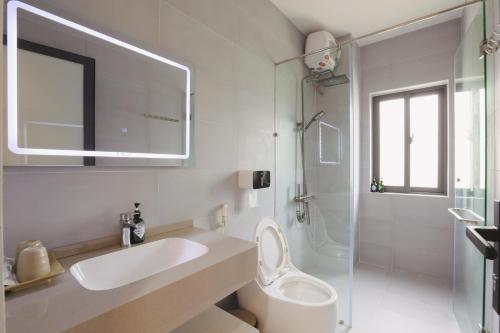 a white bathroom with a sink and a toilet at Trà Homestay in Thôn Lại Thê