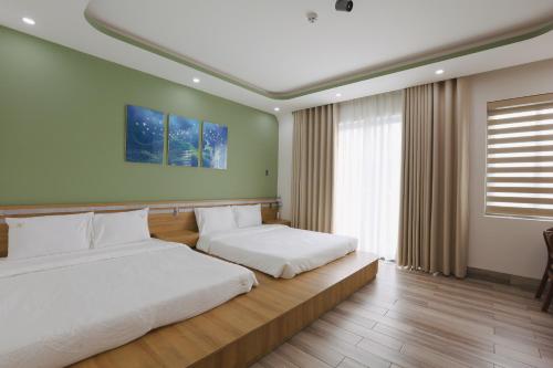 a bedroom with two beds and a large window at Trà Homestay in Thôn Lại Thê