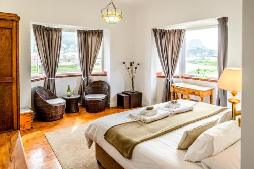 a bedroom with a large bed and two windows at The Muize in Muizenberg