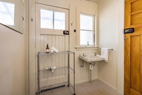 a white bathroom with a sink and a window at Ohakune's Yellow Door in Ohakune