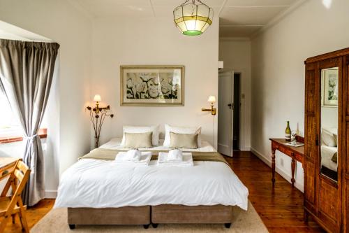 a bedroom with a large white bed and a window at The Muize in Muizenberg