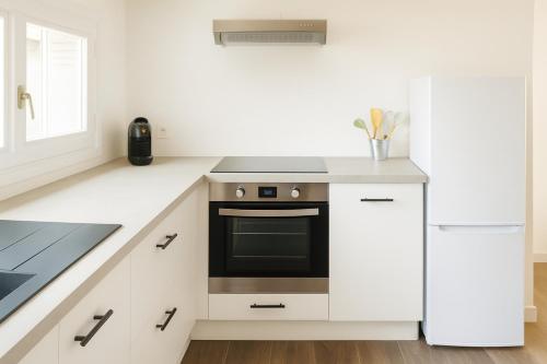 Appartement modulable في لانيميزان: مطبخ أبيض اللون مزود بموقد وثلاجة