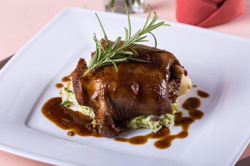 a white plate with a piece of meat with gravy and rosemary at Hotel Krzyski in Tarnów