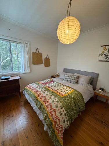 a bedroom with a bed and a large window at Manaia - A little bach near the beach in Moruya Heads