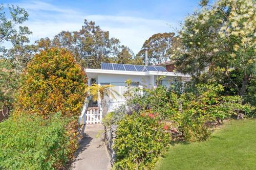a house with solar panels on the roof at Manaia - A little bach near the beach in Moruya Heads