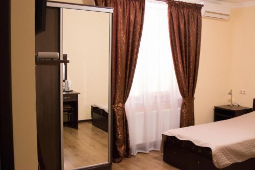 a mirror in a room with a bed and a window at Sem Uglov in Tiraspol