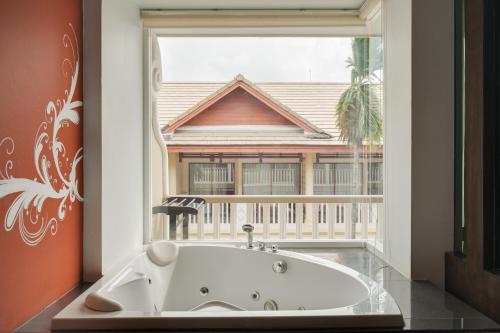 a bath tub in a room with a large window at Baan Karonburi Resort in Karon Beach