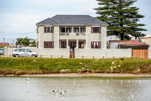 una casa con patos en el agua delante de ella en The Muize, en Muizenberg