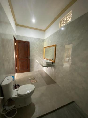 a bathroom with a toilet and a mirror on the wall at Shima House in Sukawati