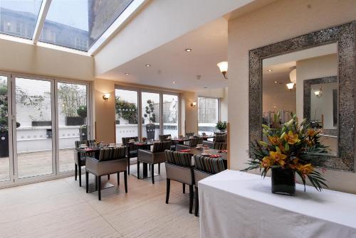 a dining room with tables and chairs and a mirror at Astors Belgravia in London