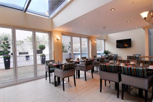 a dining room with tables and chairs and windows at Astors Belgravia in London