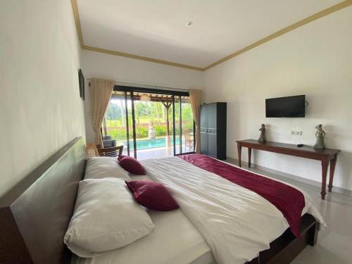 a large bed in a room with a television at Shima House in Sukawati