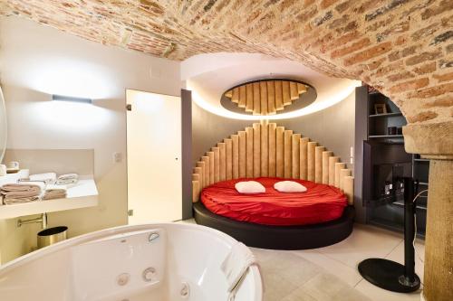 a bedroom with a red bed and a bath tub at Logis Hotel Saint-Martin in Colmar