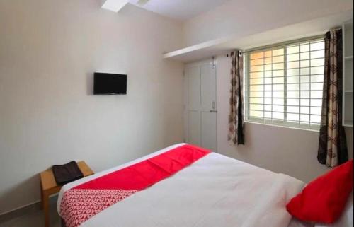 a bedroom with a bed with a red blanket and a window at SLP Residency in Mysore