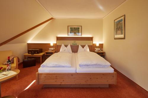 a bedroom with a large bed with white sheets at Wander- & Wellnesshotel Nägele in Höchenschwand
