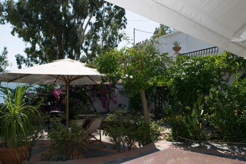 a patio with an umbrella and some plants at Roditses Beach Sea Front Apartments in Samos
