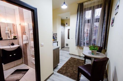 - un couloir avec une salle de bains pourvue d'un lavabo et d'une table dans l'établissement Anna Central Studio, à Sibiu