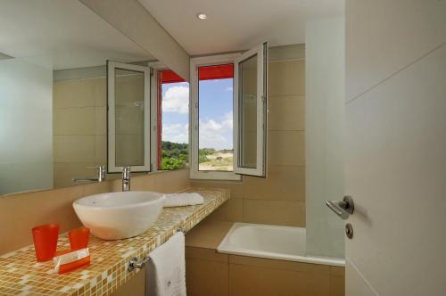 a bathroom with a sink and a tub and a window at Meca Playa in Villa Gesell
