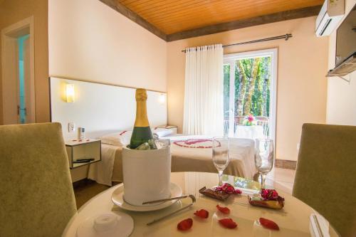 Una habitación con una cama y una mesa con una botella de champán. en Pousada do Tirol, en Gramado