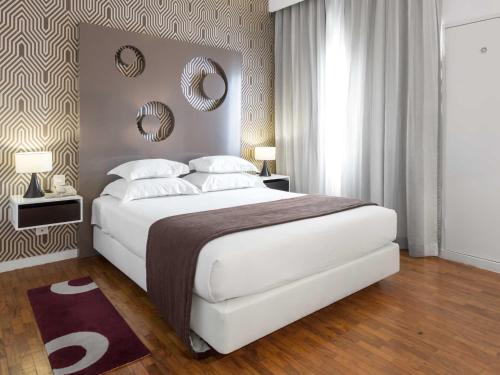 a bedroom with a large white bed and two mirrors at Hotel Tivoli Maputo in Maputo