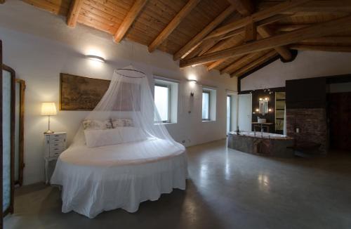 ein Schlafzimmer mit einem weißen Bett in einem Zimmer mit Holzdecken in der Unterkunft Il Riposo in San Damiano dʼAsti