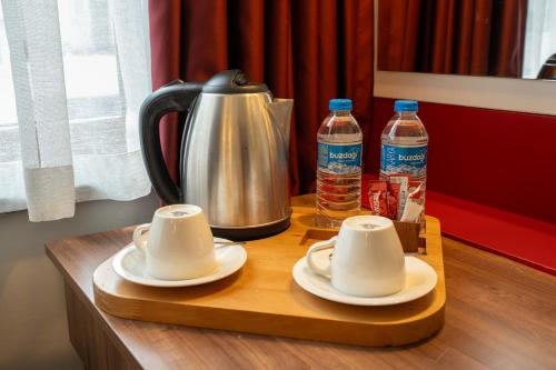 a tea kettle and two cups on a table with water bottles at Cihangir Palace Hotel in Istanbul