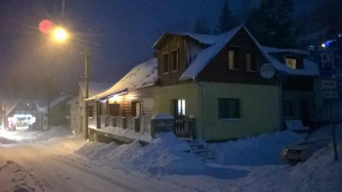 a house covered in snow at night with a street light at Apartmánek u Špičáku in Albrechtice v Jizerských horách