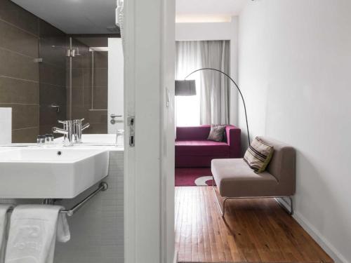 ein Bad mit einem Waschbecken und einem Sofa in einem Zimmer in der Unterkunft Hotel Tivoli Maputo in Maputo