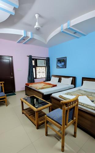 a room with two beds and a table and chairs at Hotel Aryaman in Haridwār