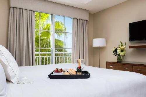 a white bed with a tray of food and a window at Blue Haven Resort- All Inclusive in Grace Bay